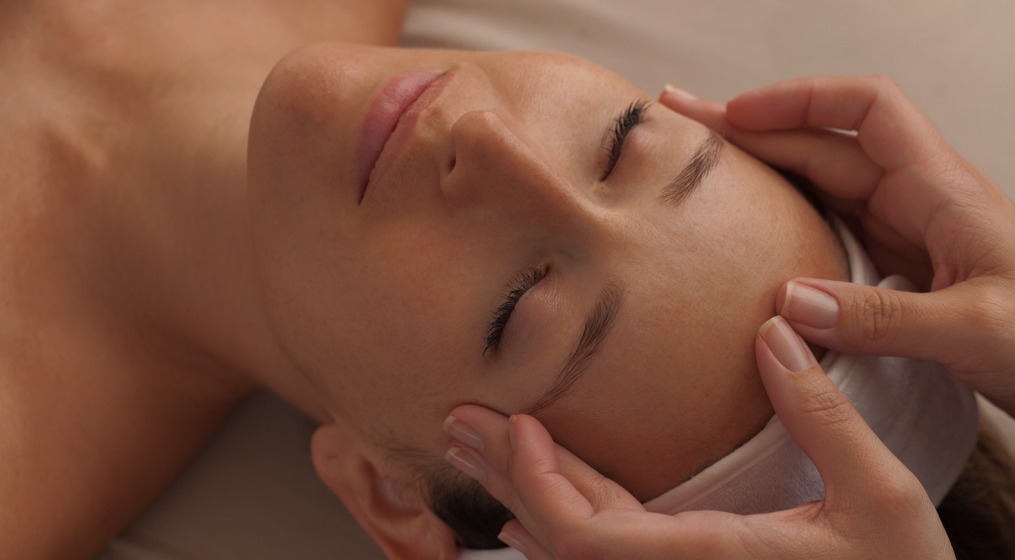 A person receiving a gentle face massage, focusing on the forehead and temples